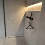 Douche italienne moderne avec niche éclairée LED, robinetterie noire et carrelage grand format – rénovation salle de bain premium réalisée à Bruxelles